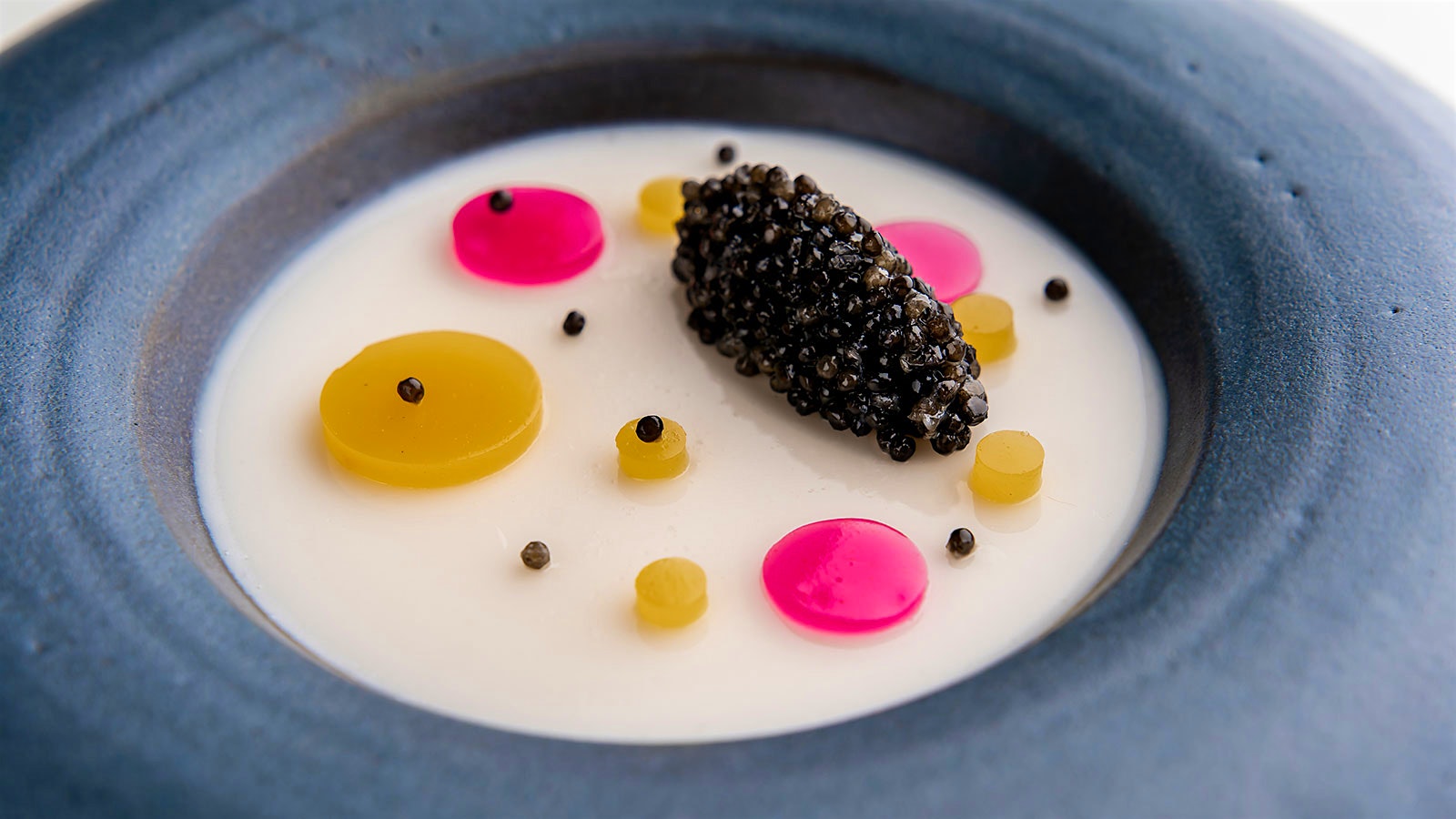 A menu item inspired by artist Yayoi Kusama with bright dots of color on a cream background, served in a stone-colored bowl